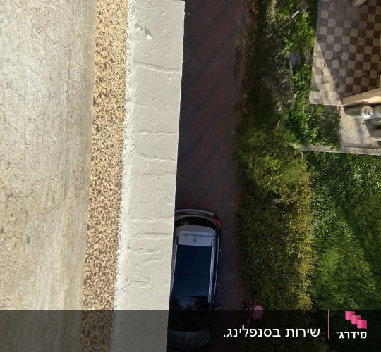 מבט מלמעלה על מכונית חונה ליד קיר בניין